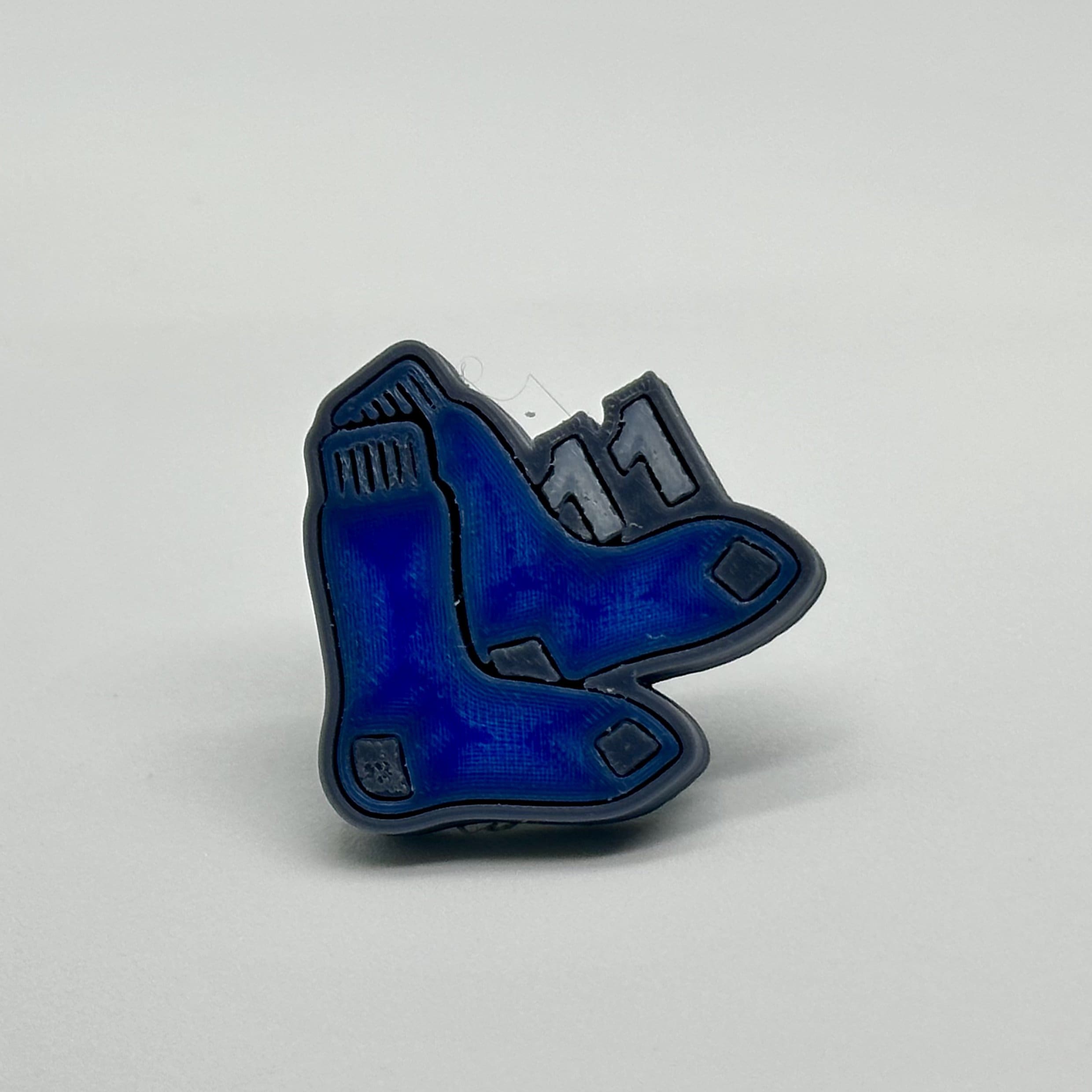 A blue and black ice skate-shaped pin against a white background.